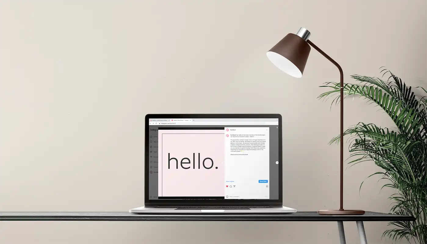 A laptop showing the word "hello" on its screen. The laptop is on a desk with a lamp and a plant.