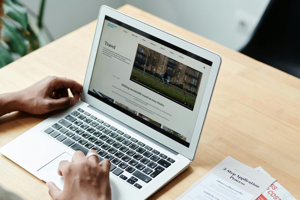 A person viewing the Alconbury Weald travel page on a laptop, displaying transport and travel information on the website.
